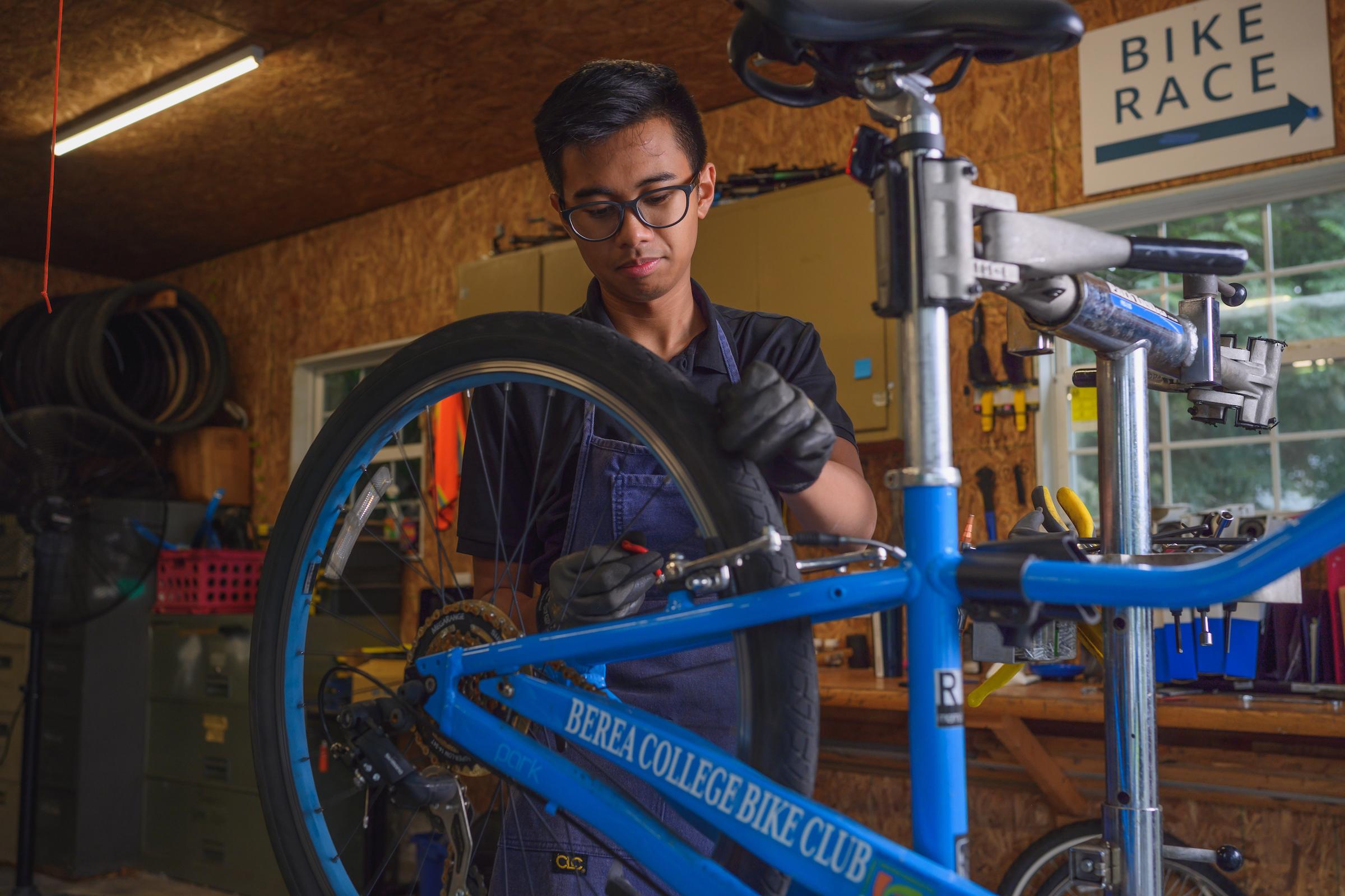 The lead repair technician performs maintenance on a bike for the Berea College Office of Sustainability bike share program.