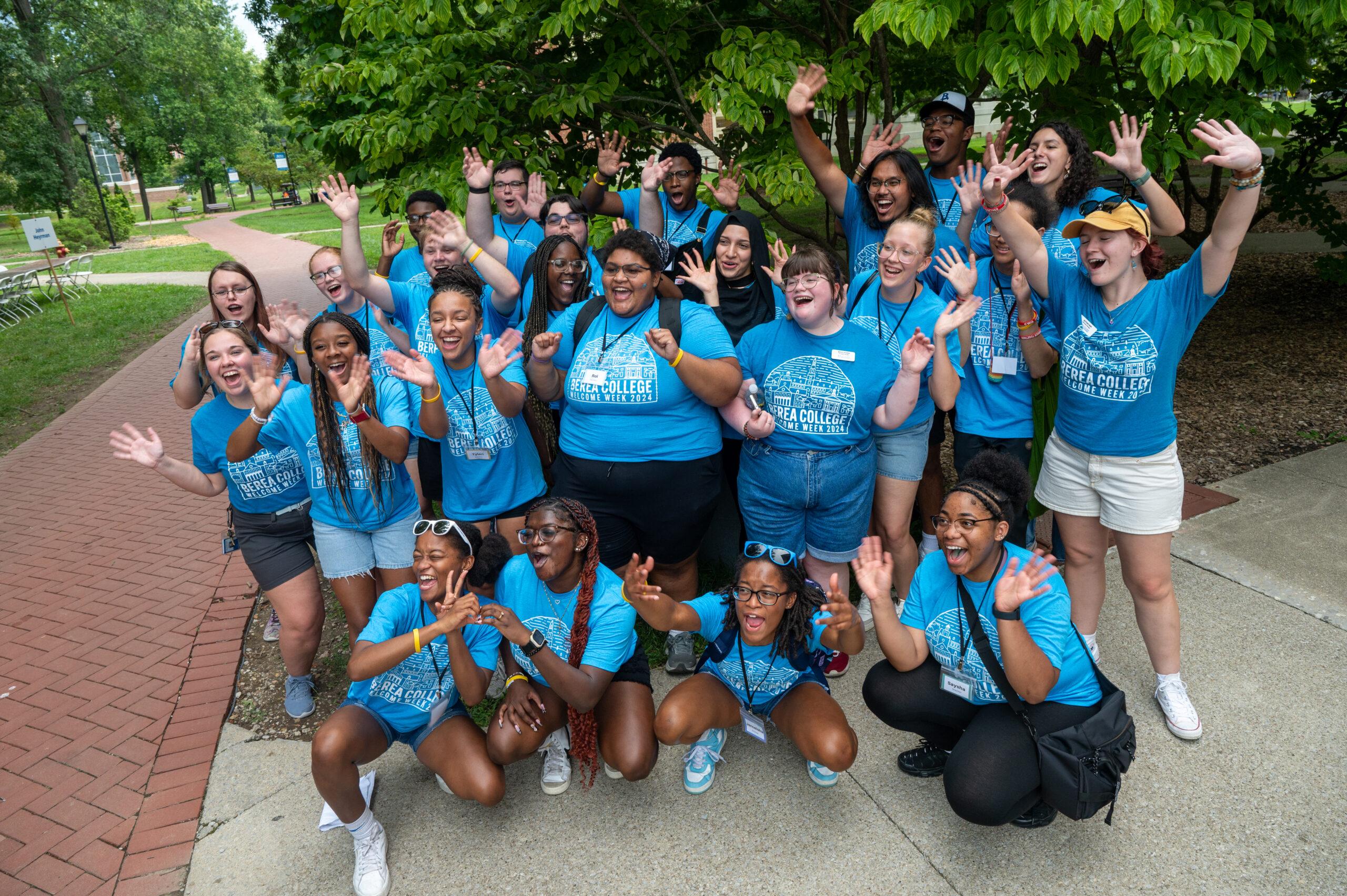A diverse group of students raises their hands in the air, celebrating a success.